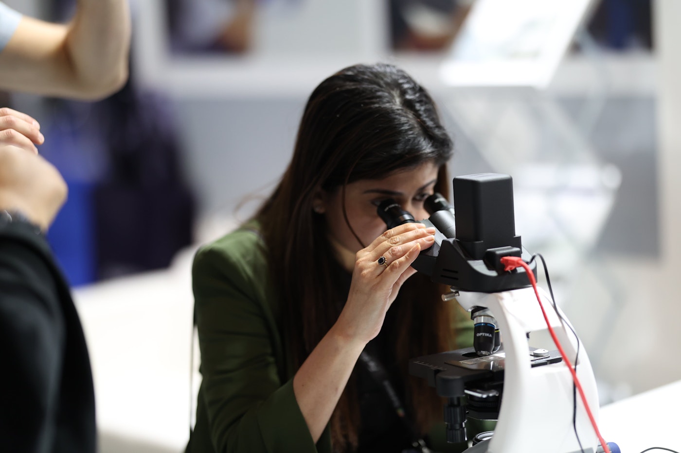 A visitor looking through a microscope at an exhibition stand